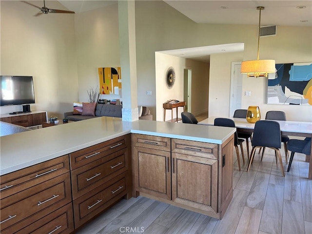 kitchen with pendant lighting, high vaulted ceiling, kitchen peninsula, and ceiling fan