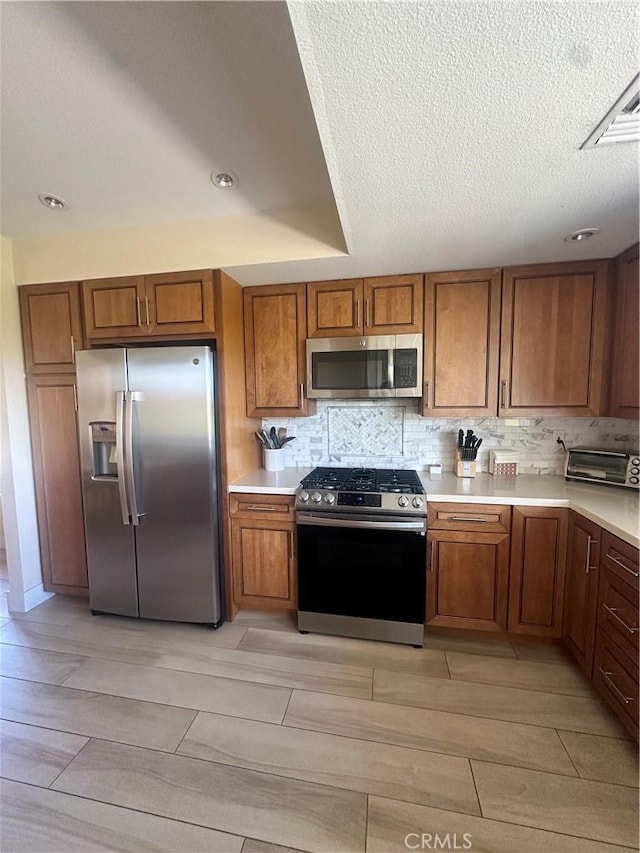 kitchen featuring tasteful backsplash, stainless steel appliances, and a textured ceiling