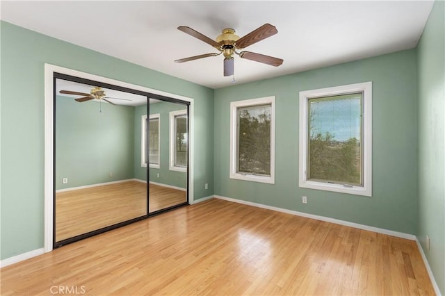 unfurnished bedroom with ceiling fan, a closet, and light wood-type flooring