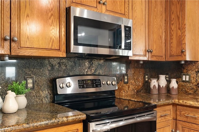 kitchen with decorative backsplash, dark stone counters, and appliances with stainless steel finishes