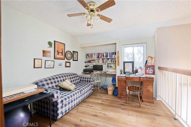 office area featuring ceiling fan, vaulted ceiling, a textured ceiling, and light wood-type flooring