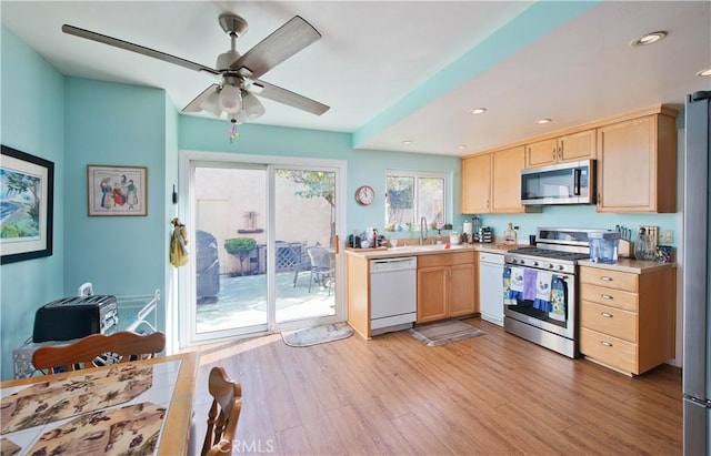 kitchen with stainless steel appliances, sink, light wood-type flooring, and light brown cabinets