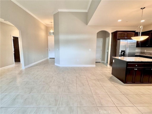 kitchen featuring crown molding, stainless steel fridge, hanging light fixtures, light stone counters, and light tile patterned flooring