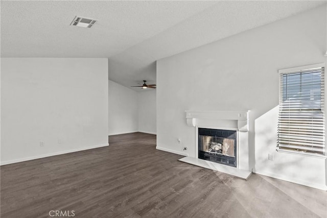 unfurnished living room featuring lofted ceiling, a textured ceiling, dark wood-type flooring, and ceiling fan