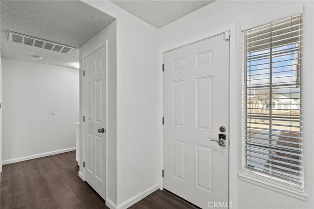 entryway with dark wood-type flooring and a textured ceiling