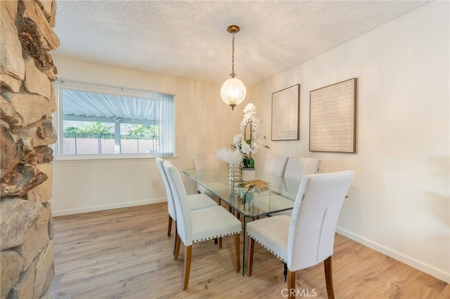 dining space with a textured ceiling and light hardwood / wood-style floors