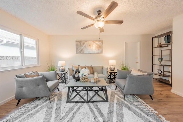 living room with ceiling fan, light hardwood / wood-style flooring, and a textured ceiling