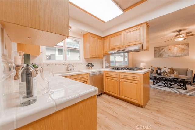 kitchen featuring appliances with stainless steel finishes, light hardwood / wood-style flooring, tile countertops, light brown cabinets, and kitchen peninsula