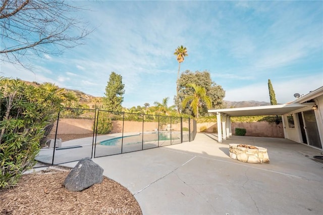 exterior space featuring a patio, an outdoor fire pit, a swimming pool, and a mountain view