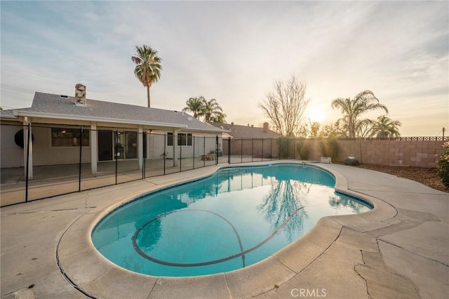 pool at dusk with a patio area