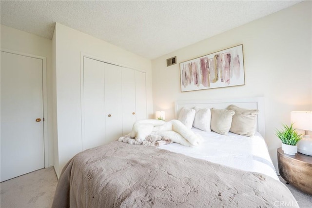 carpeted bedroom featuring a textured ceiling and a closet