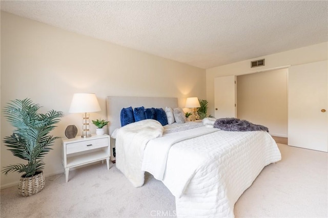 bedroom featuring a textured ceiling and light colored carpet