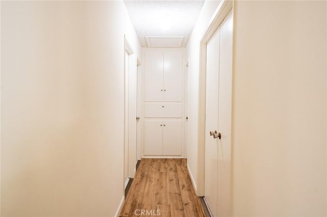 hallway with light wood-type flooring and a textured ceiling