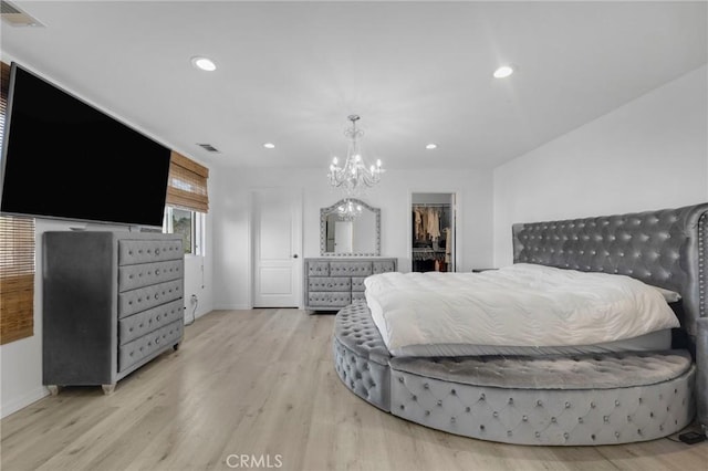 bedroom featuring a closet, a spacious closet, an inviting chandelier, and light hardwood / wood-style flooring