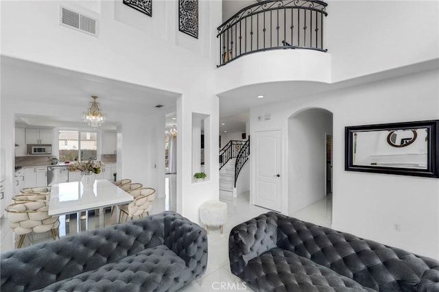 entryway with visible vents, arched walkways, an inviting chandelier, a high ceiling, and stairs