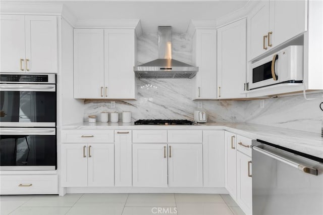 kitchen with wall chimney exhaust hood, stainless steel appliances, light stone countertops, and white cabinets