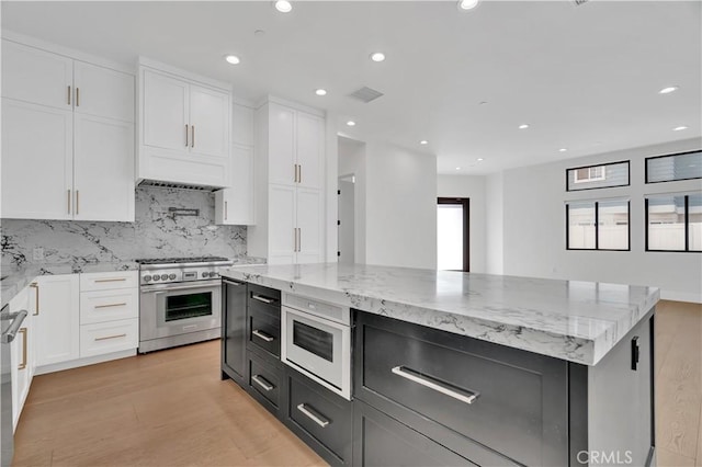 2319 Huntington Ln Unit A, Redondo Beach, CA 90278 - kitchen with high end stove, white cabinets, backsplash, light stone countertops, and light wood-type flooring