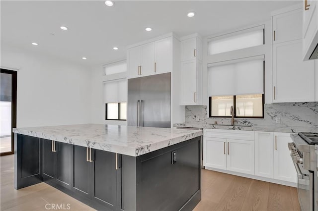 2319 Huntington Ln Unit A, Redondo Beach, CA 90278 - kitchen featuring high quality appliances, tasteful backsplash, a center island, light stone counters, and light wood finished floors