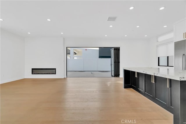 kitchen featuring light hardwood / wood-style floors, light stone counters, and white cabinets