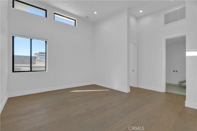 spare room with hardwood / wood-style flooring and a towering ceiling