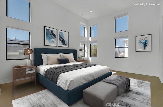 bedroom with light hardwood / wood-style floors and a towering ceiling