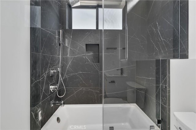 bathroom featuring toilet and tiled shower / bath