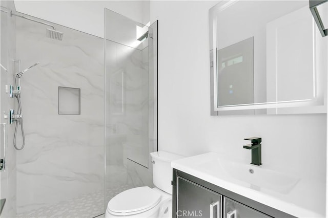 bathroom with vanity, tiled shower, and toilet