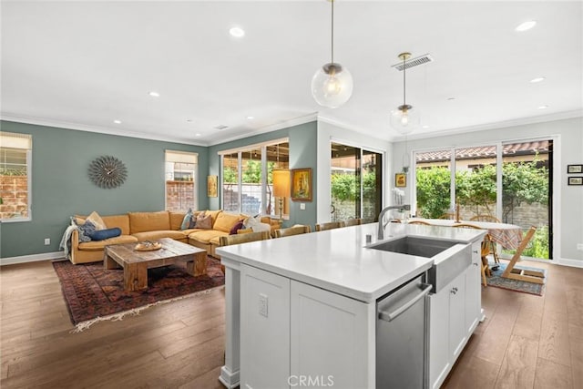 kitchen featuring decorative light fixtures, an island with sink, sink, white cabinets, and plenty of natural light