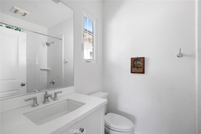 bathroom featuring vanity, toilet, and a tile shower