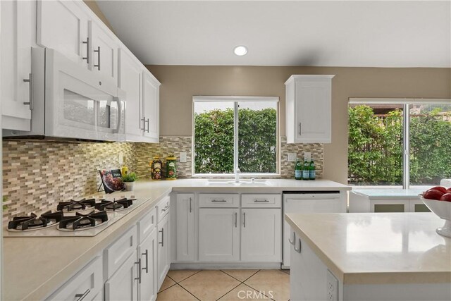 kitchen with white cabinetry, plenty of natural light, light tile patterned flooring, and white appliances