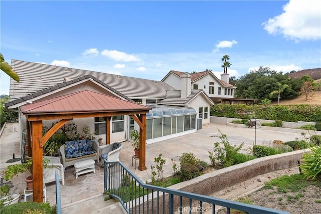 rear view of house featuring a gazebo, a sunroom, an outdoor hangout area, and a patio area