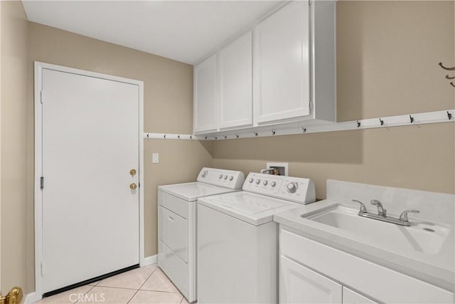 clothes washing area featuring sink, light tile patterned floors, cabinets, and washing machine and clothes dryer