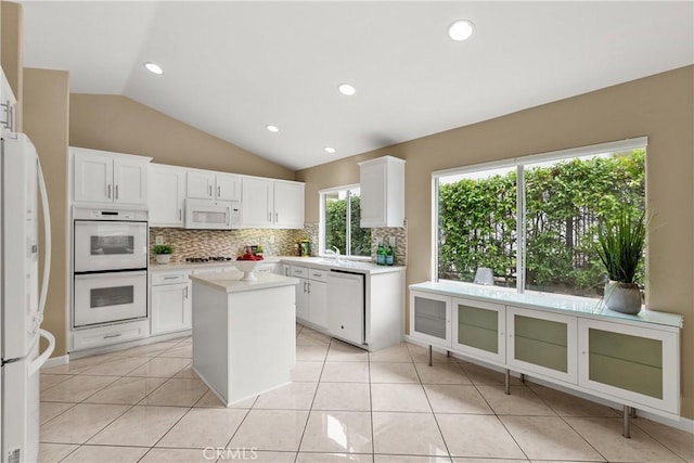 kitchen featuring white cabinetry, white appliances, decorative backsplash, and a kitchen island