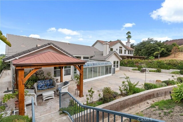 back of property featuring a gazebo, an outdoor living space, a patio area, and a sunroom