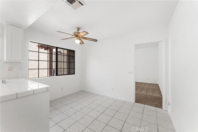 unfurnished room featuring light tile patterned flooring, visible vents, baseboards, and a ceiling fan