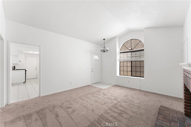 unfurnished living room featuring an inviting chandelier, a brick fireplace, lofted ceiling, and carpet floors