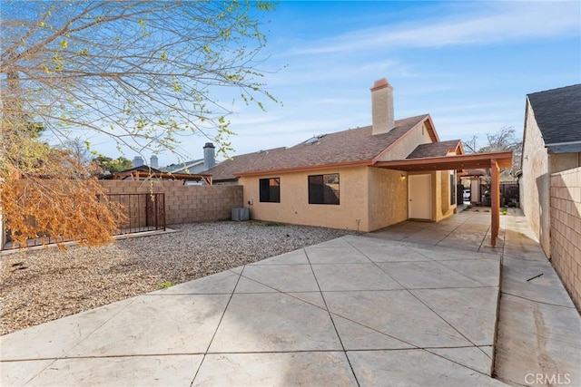 rear view of property with stucco siding, a patio, a fenced backyard, and a chimney