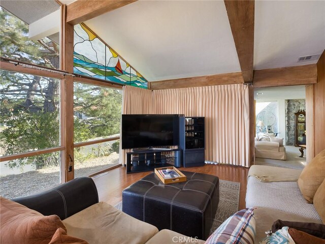 living room with vaulted ceiling with beams, a wealth of natural light, and wood-type flooring