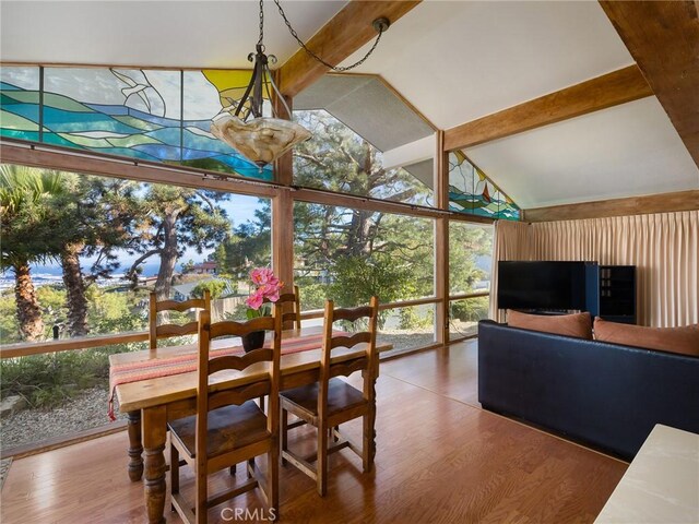 dining area featuring vaulted ceiling with beams, wood-type flooring, and expansive windows