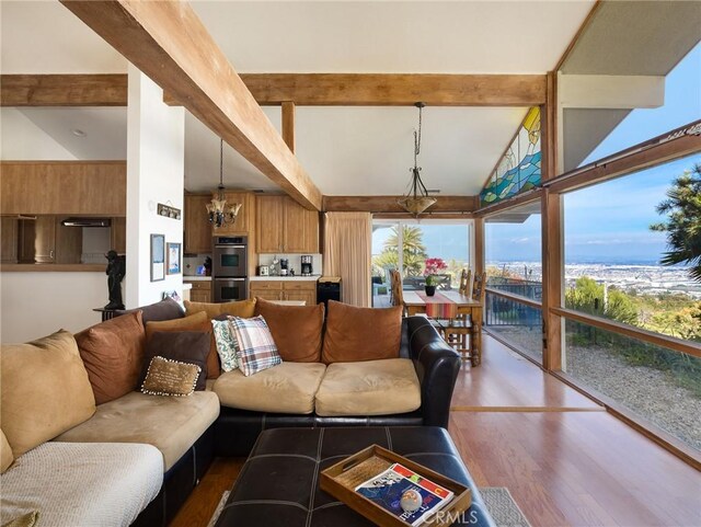 living room featuring dark wood-type flooring, a chandelier, and vaulted ceiling with beams