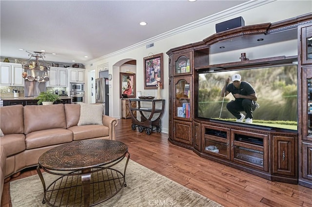 living area featuring arched walkways, crown molding, light wood finished floors, recessed lighting, and visible vents