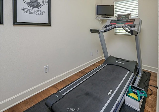 exercise room with dark wood-style floors and baseboards