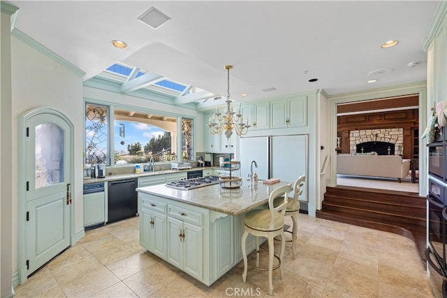 kitchen with a kitchen breakfast bar, decorative light fixtures, a center island, black appliances, and a notable chandelier