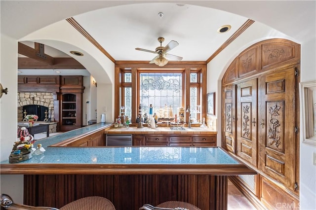 bar with dishwasher, a stone fireplace, bar, and crown molding