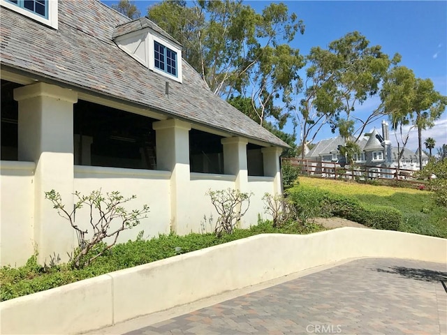 view of side of home featuring a high end roof and stucco siding