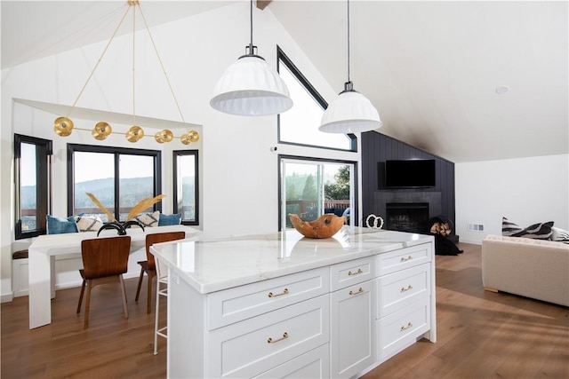 kitchen with a kitchen island, wood-type flooring, white cabinets, hanging light fixtures, and light stone counters