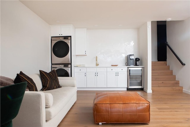 interior space with wine cooler, white cabinetry, stacked washer and clothes dryer, and light hardwood / wood-style floors