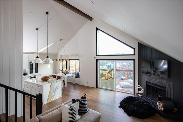 living room featuring a fireplace, wood-type flooring, high vaulted ceiling, and beamed ceiling