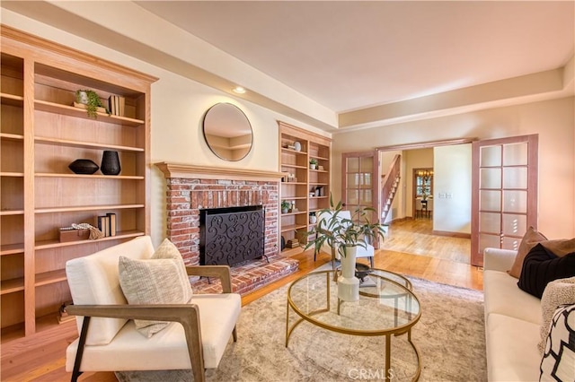 living room featuring built in shelves, a fireplace, and wood finished floors