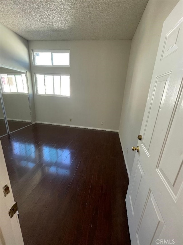 empty room with dark hardwood / wood-style floors and a textured ceiling